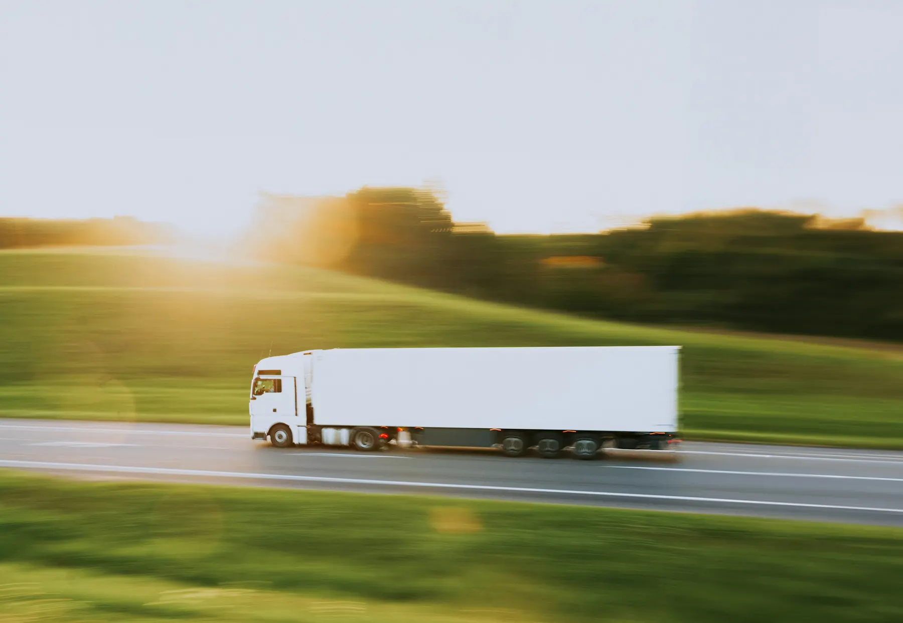 White delivery truck on a highway in late afternoon sun