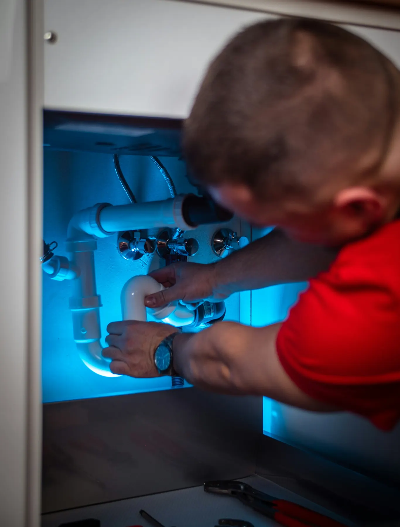 Plumber repairing drain pipes under a sink