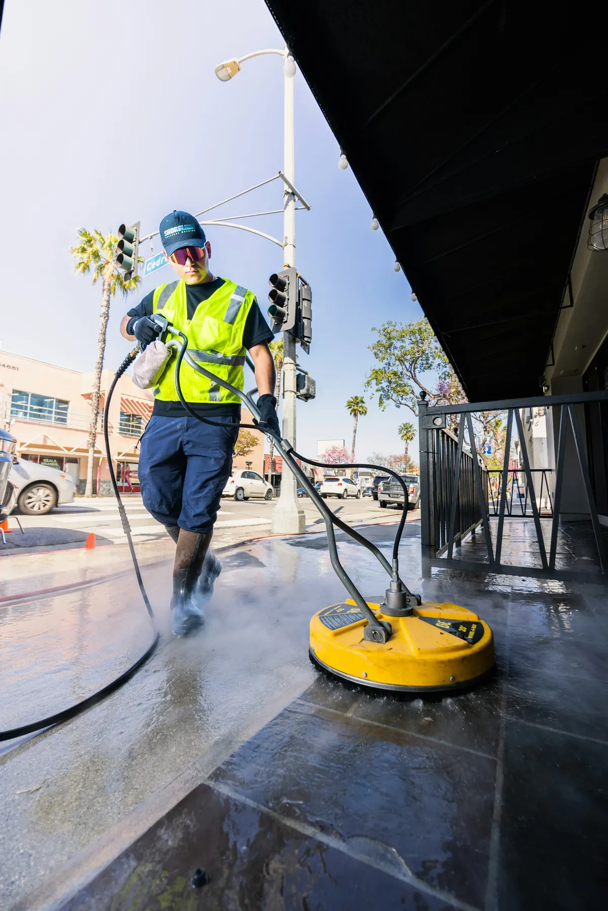 Worker pressure washing pavement with a surface cleaner